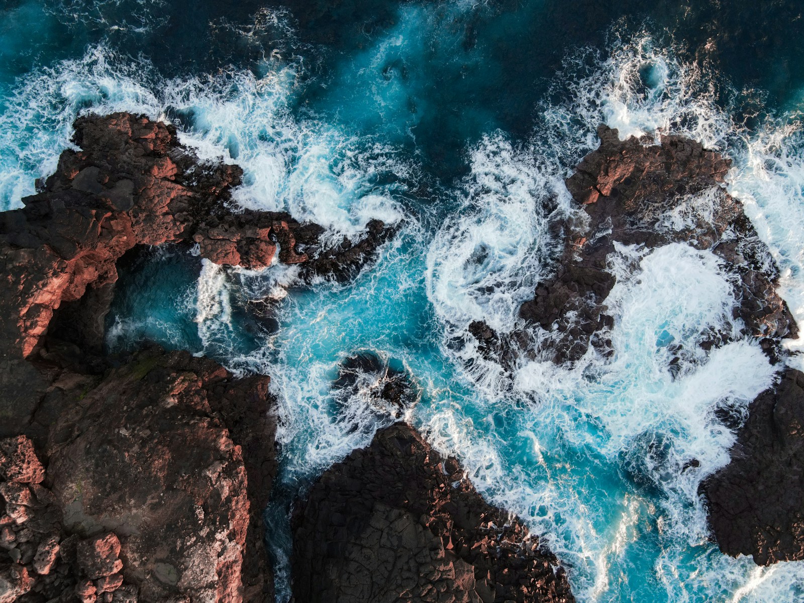 Ocean surf washing through sunlit coastal rock formations
